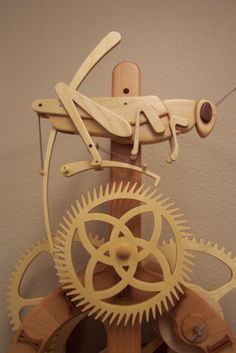 a clock made out of wooden gears with an insect on it's back end