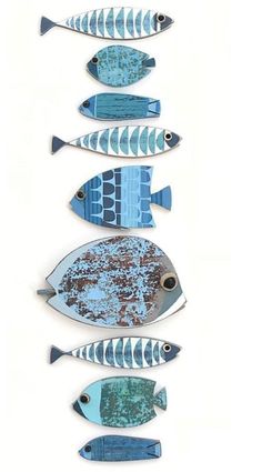 five blue and white fish are lined up in the shape of a line on a white surface