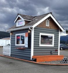 a small gray and white building sitting on top of a parking lot