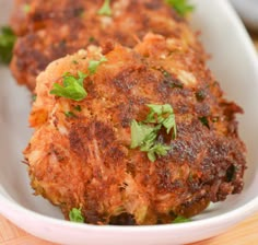 two crab cakes in a white bowl on a wooden table