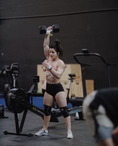 a woman with no shirt on lifting a barbell