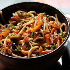 a bowl filled with noodles and vegetables on top of a table