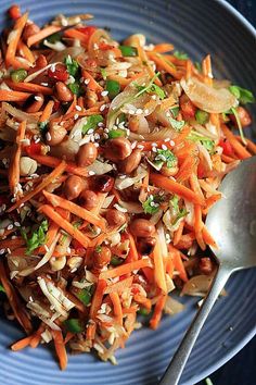 a blue plate topped with carrots and rice next to a silver spoon on top of a table