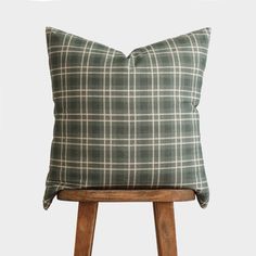 a green plaid pillow sitting on top of a wooden stool