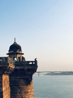 an old brick tower with a dome on top overlooking the water and bridge in the distance