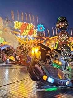 an amusement park ride at night with lights on and people riding in the back ground