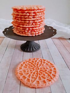 an orange cake sitting on top of a wooden table next to a plate with cookies