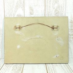 an old white box sitting on top of a wooden table next to a wood wall