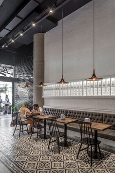 people sitting at tables in a restaurant with black and white floor tiles on the walls