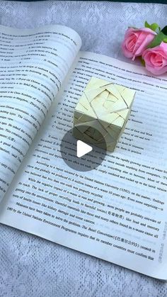 an origami object sitting on top of a book next to flowers and a pen