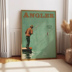 an old angler poster on the wall next to a vase with dry grass in it