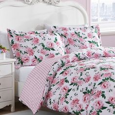 a bed with pink and white flowers on it in a bedroom next to a window