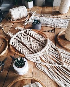 several different types of yarns and plants on a wooden table next to two potted succulents