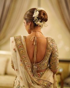 the back of a woman's dress with flowers in her hair and an elaborate headpiece