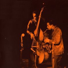 two men are playing instruments in front of microphones