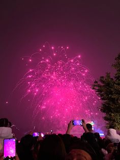 people are taking pictures with their cell phones as fireworks go off in the sky