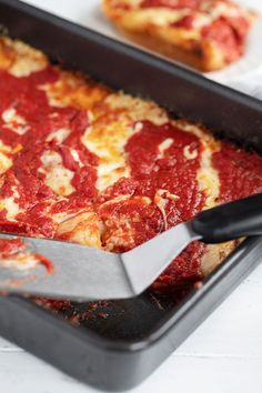 a deep dish pizza with pepperoni and cheese is being cut by a large knife