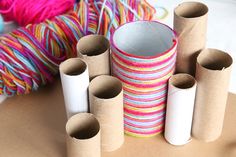 several rolls of toilet paper sitting on top of a table next to yarn and scissors