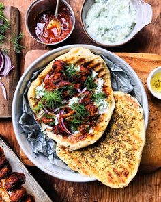 two pita breads are on a plate with some sauce and other food items