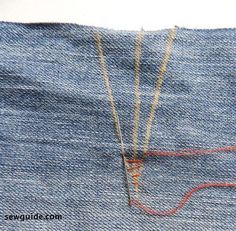 an old pair of jeans has been stitched together with red thread and yellow pins