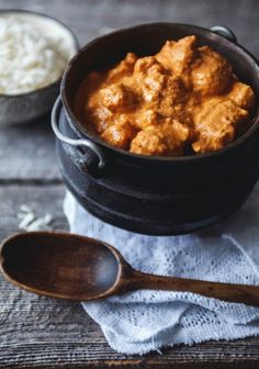 a wooden spoon sitting next to a black pot filled with food on top of a table