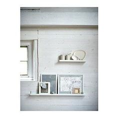 some white shelves with pictures and vases on them in a room that is painted white