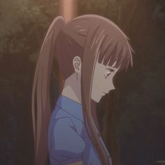 a girl with long hair standing in front of trees and looking at the ground while wearing a blue shirt