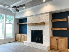 an empty living room with a fireplace and built - in shelving