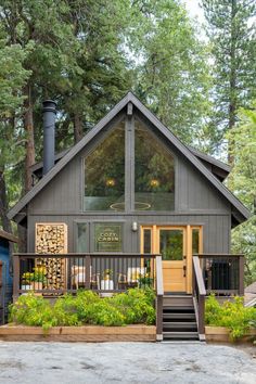 a small cabin in the woods with stairs leading up to it's front door