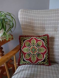 a chair with a pillow on it next to a potted plant