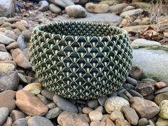 a large woven basket sitting on top of some rocks next to another rock and grass planter