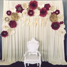 a chair sitting in front of a backdrop with flowers