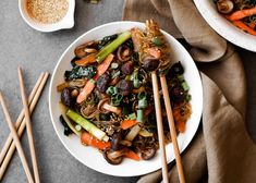 a bowl filled with noodles and vegetables next to chopsticks on top of a table