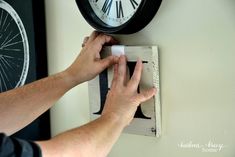 a person adjusting the time on a wall clock