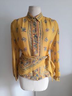 Vintage 80's semi sheer yellow silk shirt, blouse, with a floral print in shades of teal and pink.   A matching silk triangle that can be used as a scarf or a belt makes the set. Ovesized shoulders with small, soft shoulder pads and long sleeves with cuffs. Button up front with small golden lucite buttons. No tags, but it dresses a size M/L, depending on the desired fit. Please check measurements for accuracy: Shoulders: 40cm/15.8" Bust: 102cm/40.1" Length: 58cm/22.8" Sleeve: 59cm/23.2" In very Yellow Floral Print Silk Blouse, Yellow Floral Print Silk Tops, Yellow Silk Top With Floral Print, Yellow Silk Blouse With Floral Print, Vintage Printed Silk Tops, Vintage Silk Blouse With Floral Print, Yellow Bohemian Blouse For Daywear, Vintage Silk Top With Floral Print, Vintage Printed Blouse For Work