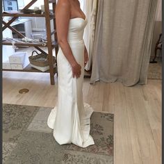 a woman standing in front of a mirror wearing a white dress and looking at the camera