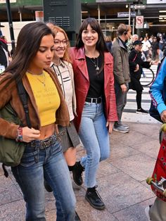 three girls are walking down the street with their skateboards in hand and one girl is smiling at the camera