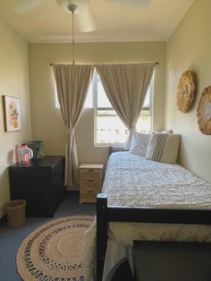 a bed room with a neatly made bed and a rug on the floor in front of a window