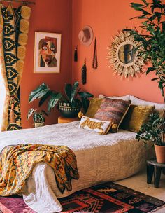 a bedroom with orange walls and plants in the corner