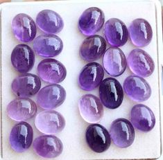 a bunch of purple stones sitting on top of a white tray