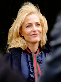 a woman with blonde hair wearing a blue shirt and red, green, and white striped tie