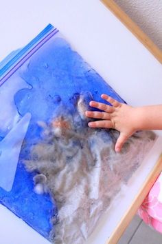 a child's hand is on top of a blue and white beach squish bag