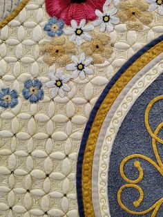 closeup of an ornate design on a quilted piece of fabric with flowers and swirls