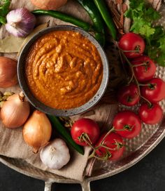 a bowl of tomato sauce surrounded by vegetables