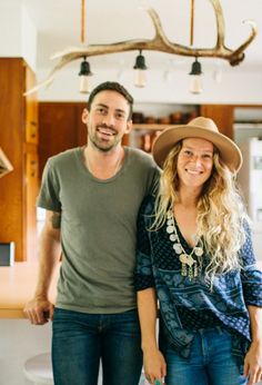 a man standing next to a woman in a kitchen with antlers on the ceiling