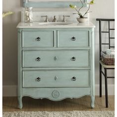 a blue dresser with a mirror and flowers on it's top, in front of a white wall