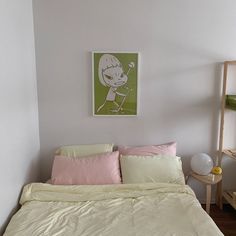 a bed with white sheets and pink pillows in a small room next to a painting on the wall