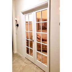 an open door leading into a bedroom with white walls and tile flooring on either side