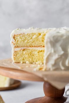 a close up of a slice of cake with white frosting on a wooden platter