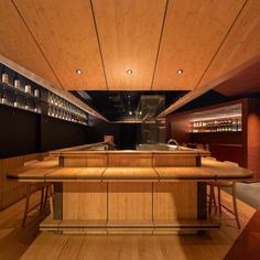 an empty bar with wooden counter tops and stools in a room filled with bottles